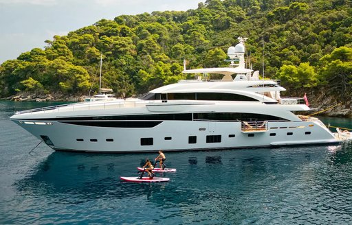 Charter yacht MIRAGE IV at anchor with elevated green terrain aft