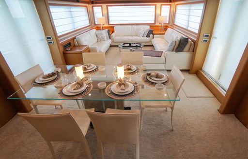 Light colored interiors of charter yacht NOMADA, with dining table in foreground and sofas in background