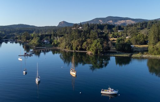 Boats at anchor in completely calm Deer Harbor on Orcas Island in the San Juans as golden hour approaches.