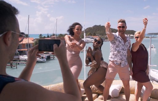 Person taking photo of four guests partying on boat