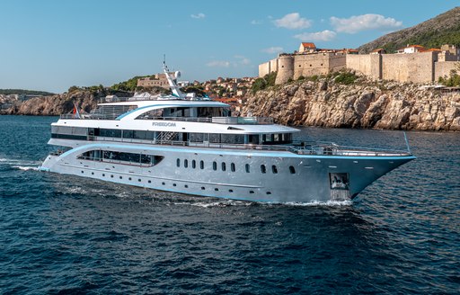 Charter yacht FREEDOM underway with adjacent cliffs