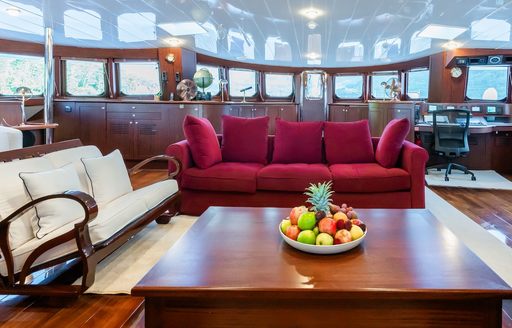 Interiors onboard catamaran yacht charter DOUCE FRANCE, burgundy sofa central with surrounding glazing