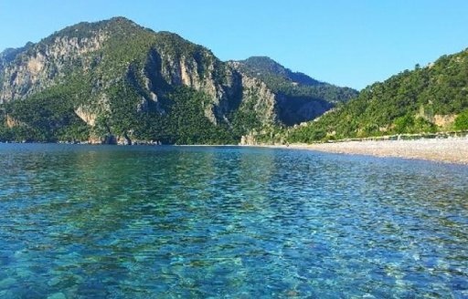 crystal clear waters and pine-covered mountains backing Cirali Beach in Turkey