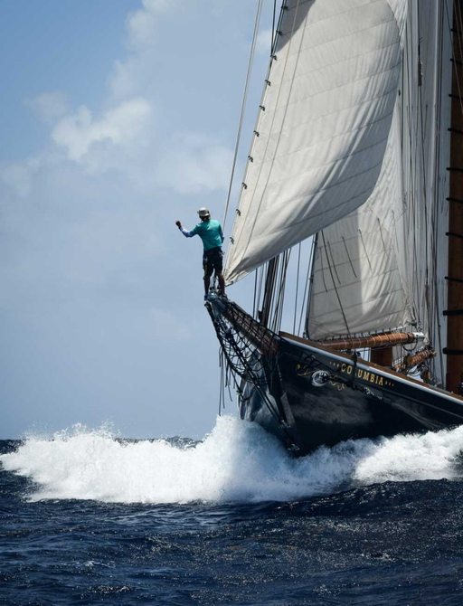 Man on bowsprit of classic yacht at regatta in Antigua