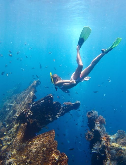 Charter guest diving on a breath hold and fining in blue transparent sea near wreck USAT Liberty, Tulamben, Indonesia