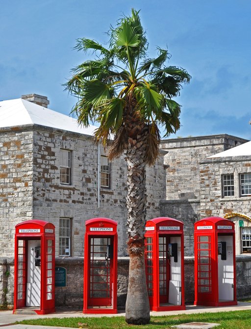 four red phone boxes line up in a row alongside colonial building in Bermuda