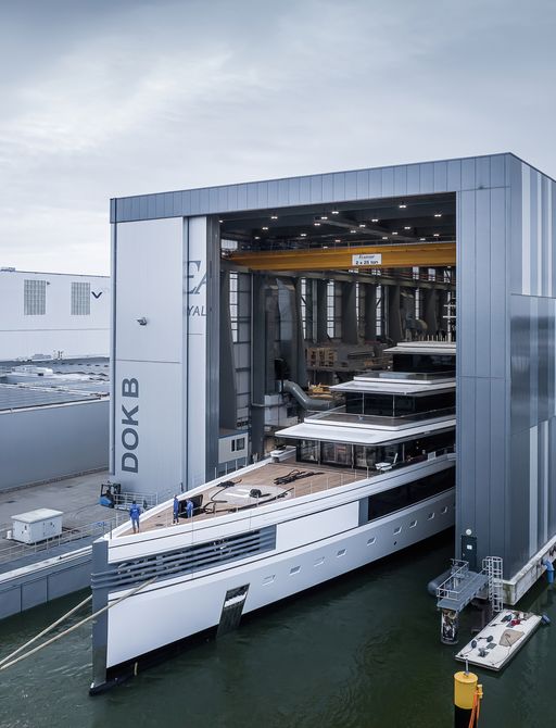 Forward view watching Feadship Project 1011 bow emerging from construction shed