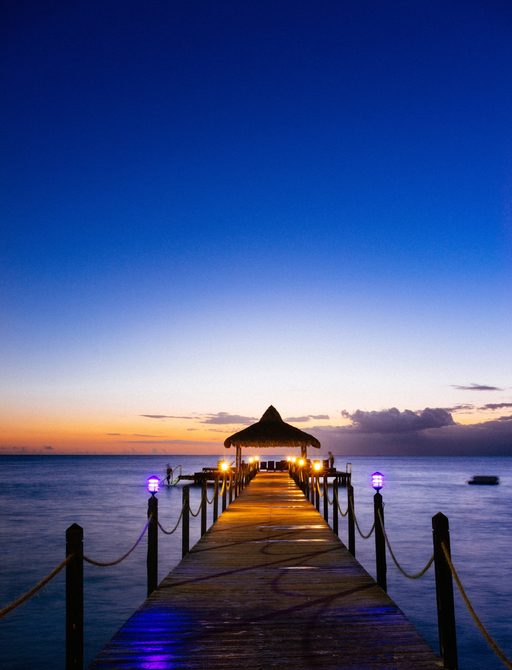 a pier in a secluded Bahamas beach as the sun sets