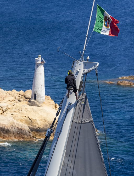 Sailor stands on mast of sailing yacht during Loro Piana superyacht regatta