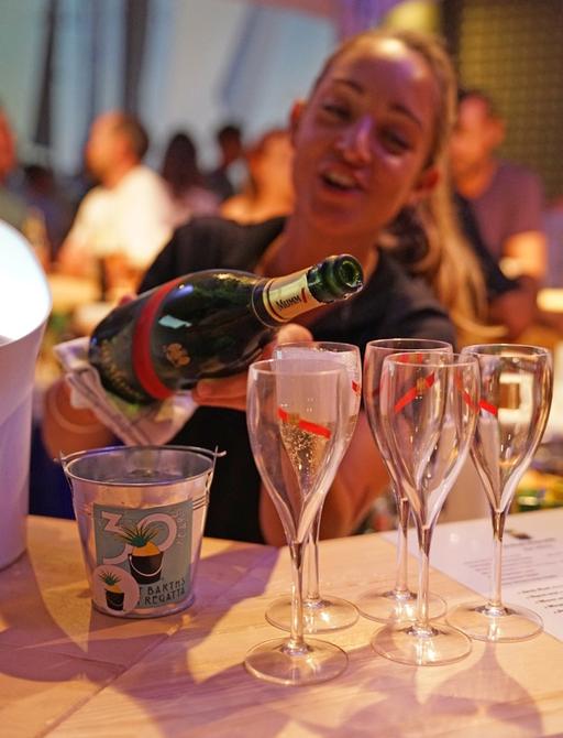 Woman pours champagne at after-party at St Barths Bucket Regatta