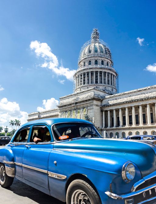 blue vintage car in Havana driving past Spanish colonial buildings