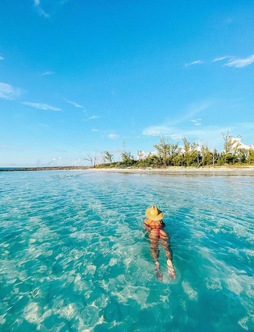 Woman wearing hat swimming towards the shore in Manjack Cay 