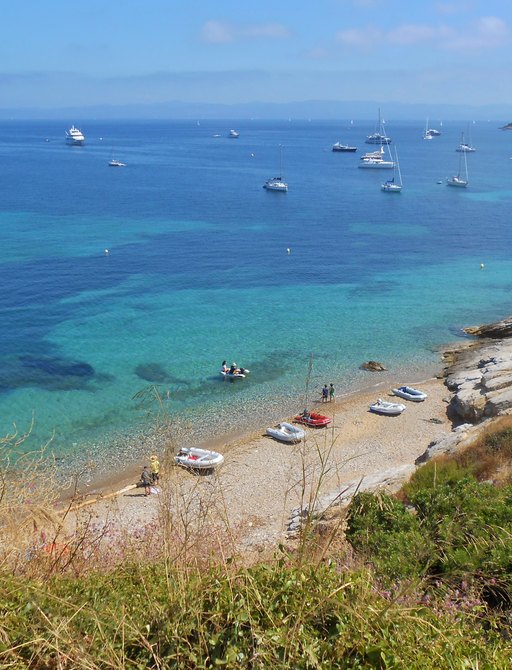 Sandy beach in the South of France, with clear blue sea and boats on the water