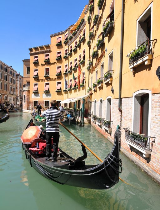 gondola cruises up a narrow canal in Venice, Italy