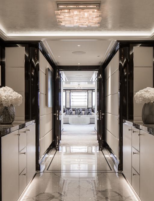 looking down a corridor on luxury yacht aquila with marble floors, white flowers and crystal chandeliers