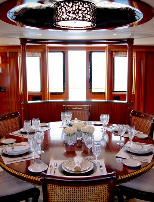 Wood paneled dining room on luxury yacht M4.  Circular table is laid in the middle. 