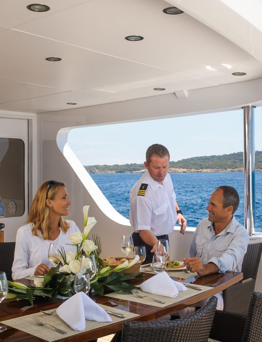 guests dining on aft deck of luxury yacht L’Albatros