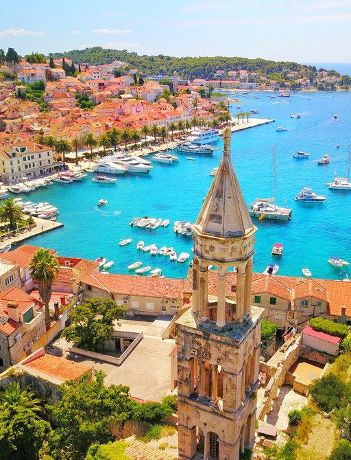 Beautoful old town of Croatia with steeple in the foreground and yachts in a turquoise harbor