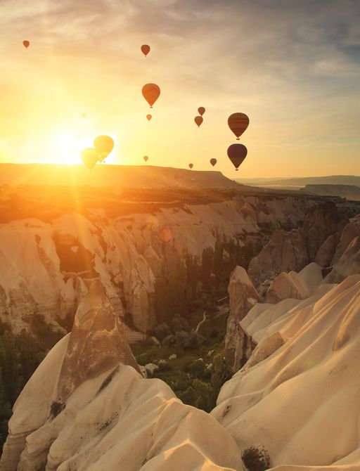 Hot air balloons against a rising morning sun in the mountains in Turkey