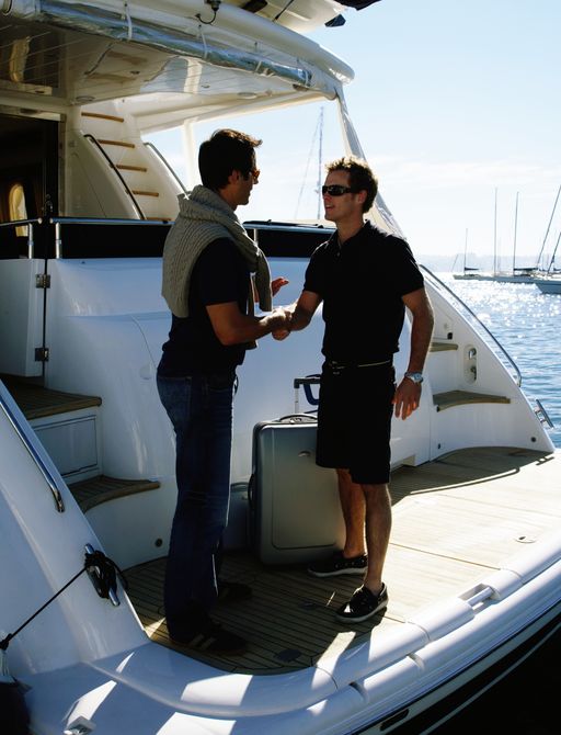 A guest shakes hands with a deck hand on a yacht's swim platform