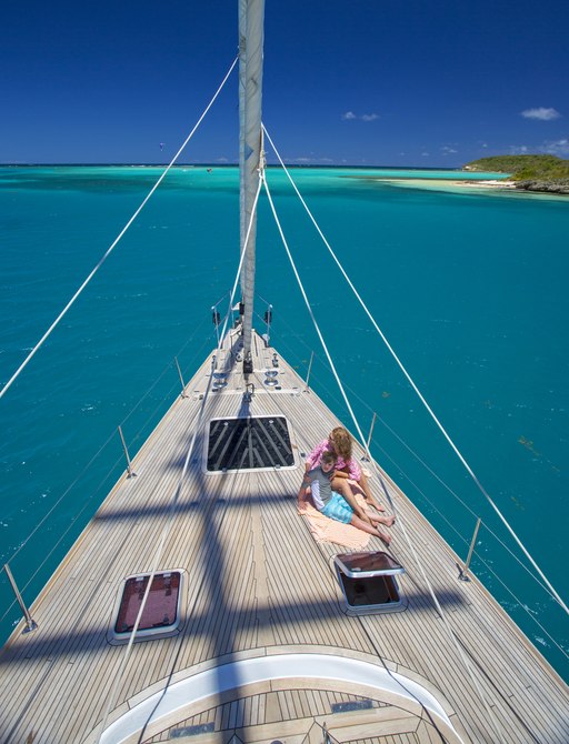 charter guests relax on foredeck of sailing yacht JUPITER as she cruises the beautiful waters of the Caribbean