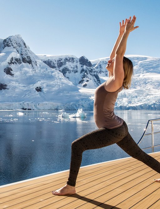 Woman doing yoga on a deck of a superyacht charter LEGEND in Antarctica