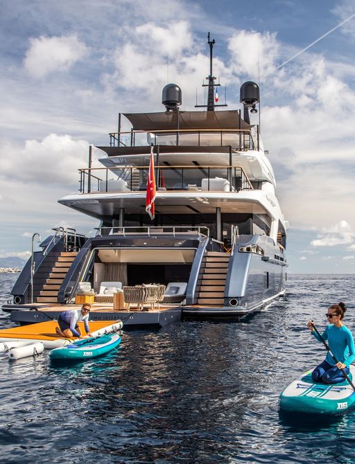 View of superyacht SEVERIN'S stern, with beach club and guest on kayak in water